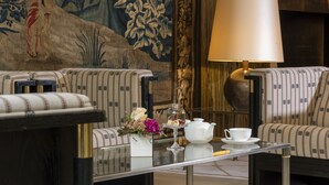 A room with two patterned sofas, a glass coffee table with a teapot, cup, and flowers, and a large lamp. - Best Western Premier Grand Hotel Russischer Hof (Weimar)
