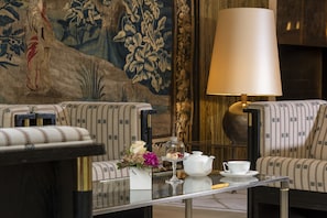 A room with two patterned sofas, a glass coffee table with a teapot, cup, and flowers, and a large lamp. - Best Western Premier Grand Hotel Russischer Hof (Weimar)
