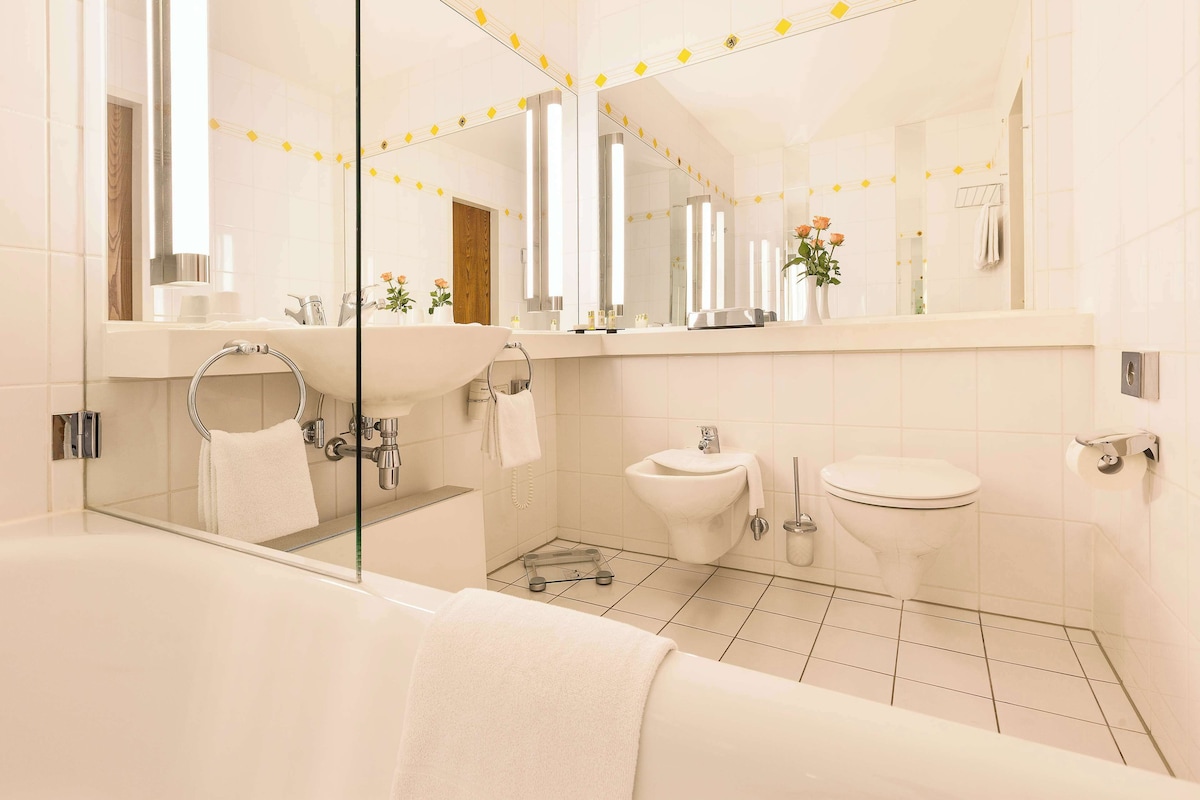 A modern bathroom with a glass-enclosed shower, a large sink, a toilet, and a bathtub.