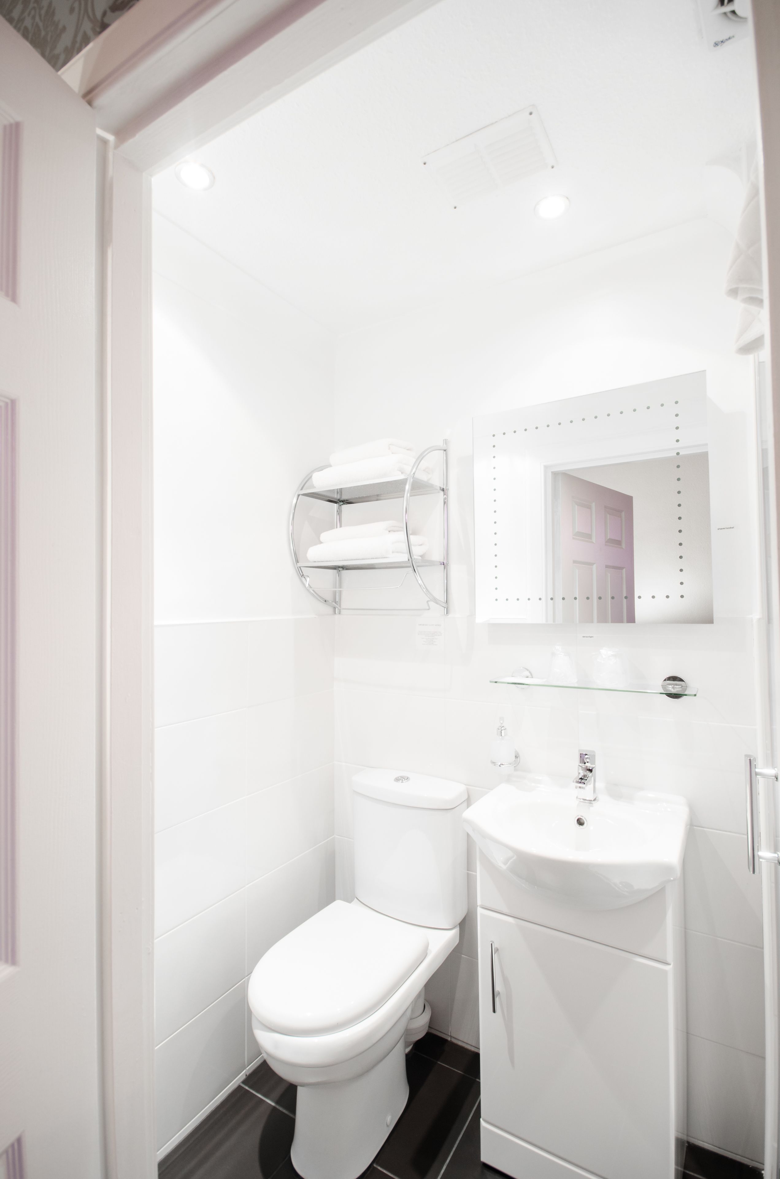A modern bathroom with a toilet, sink, and towel rack.