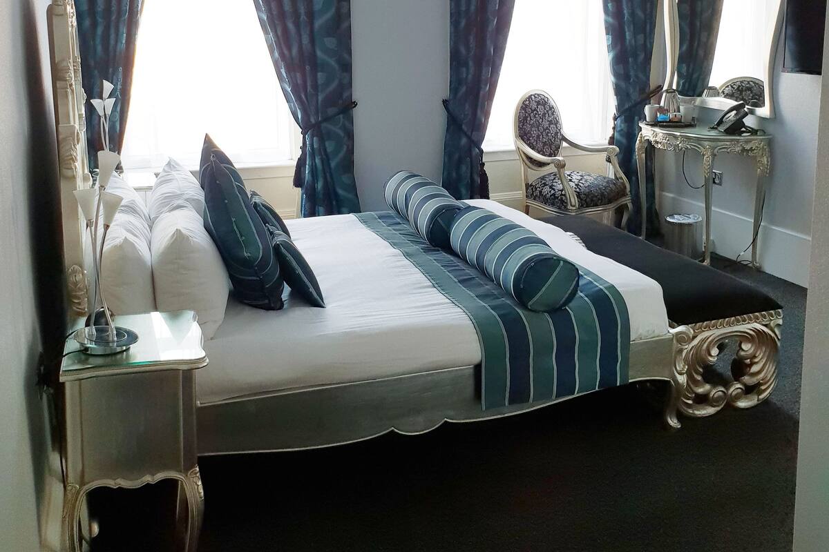 A hotel room with a large bed, two bedside tables, a mirror, and a chair.