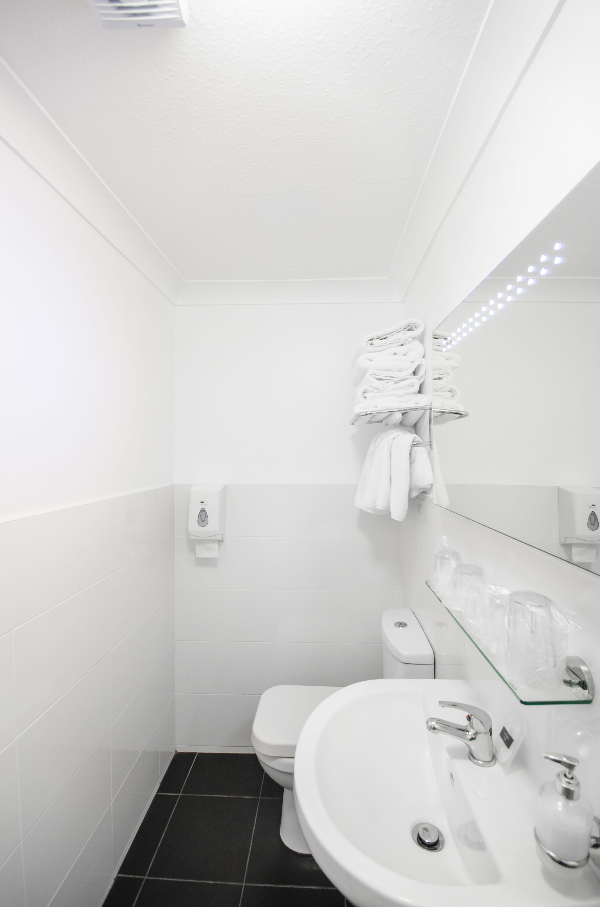 Une salle de bain moderne avec un lavabo, des toilettes et un porte-serviettes, le tout de couleur blanche.