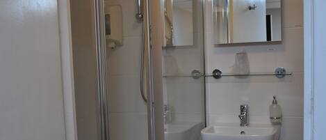 A modern bathroom with a glass-enclosed shower, a white sink, and a toilet.