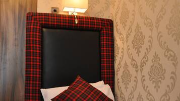 Une chambre d’hôtel avec un lit, une table de chevet, une lampe et un papier peint à motifs.