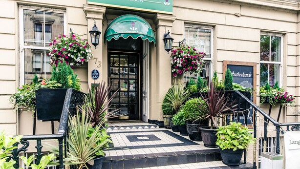 El Hotel Argyll en Glasgow, con una fachada clásica, un toldo verde y plantas en macetas en la entrada.