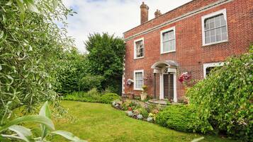 A traditional brick house with a well-maintained garden and a front door with a flower basket.