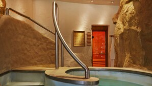 A spa area with a hot tub, a wooden door, and a stone wall. - ACHAT Hotel Magdeburg (Magdeburg)