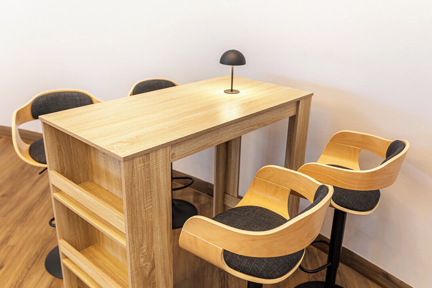A wooden table with a lamp, surrounded by four chairs with cushioned seats.
