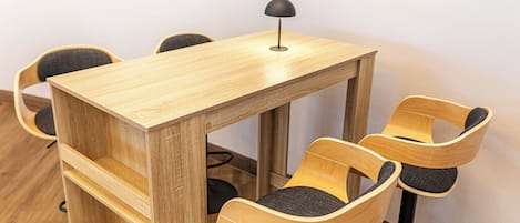 A wooden table with a lamp, surrounded by four chairs with cushioned seats.