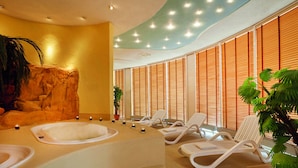 A spa area with two hot tubs, lounge chairs, and a rock wall. - ACHAT Hotel Magdeburg (Magdeburg)