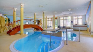 An indoor swimming pool with a red bridge, columns, and a reception area with a window. - ACHAT Hotel Magdeburg (Magdeburg)