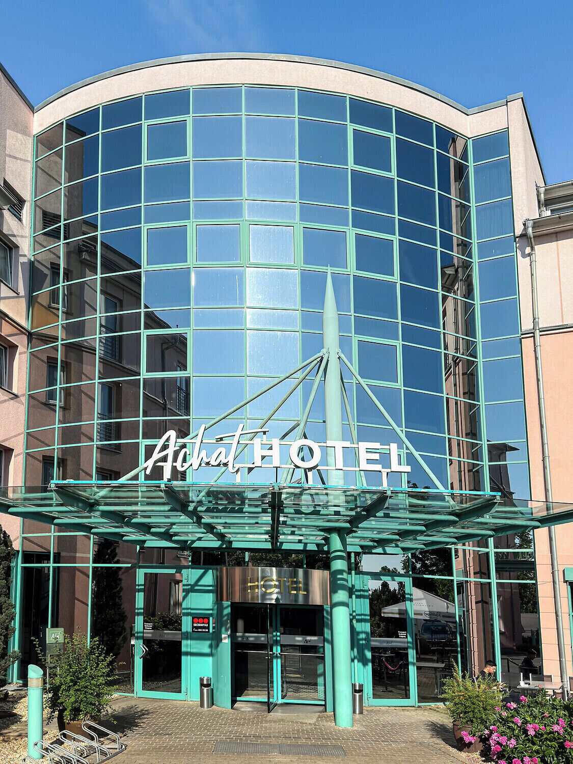 A modern hotel with a curved glass facade and a prominent entrance.