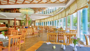 A spacious hotel dining area with wooden furniture, large windows, and a high ceiling with wooden beams. - ACHAT Hotel Magdeburg (Magdeburg)