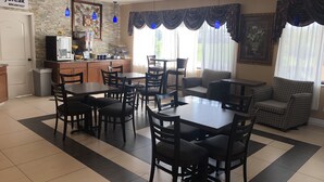 Ein Hotel-Essbereich mit Küche, Esstischen, Stühlen und einer Couch.