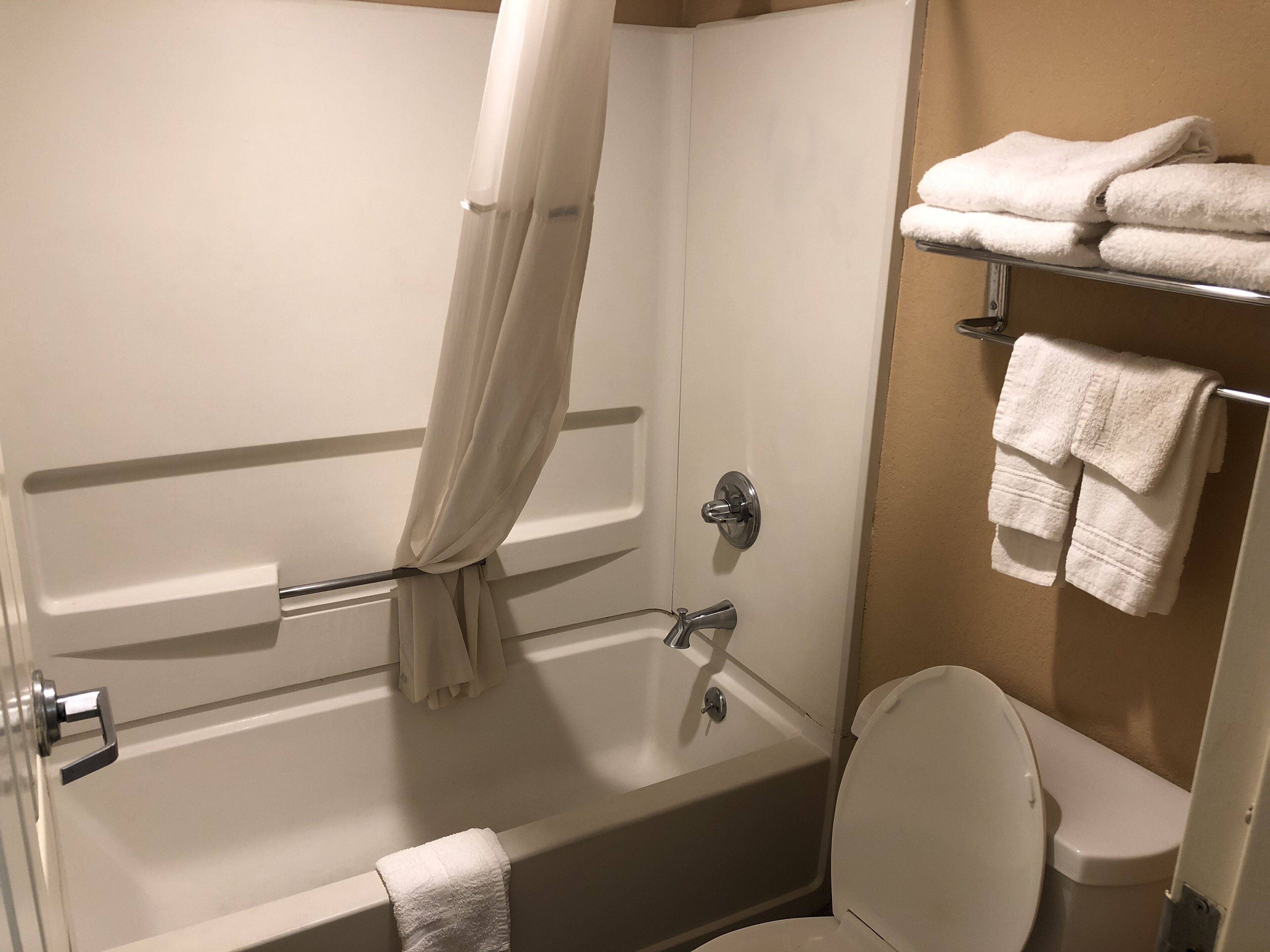 A bathroom with a bathtub, toilet, and towel rack.