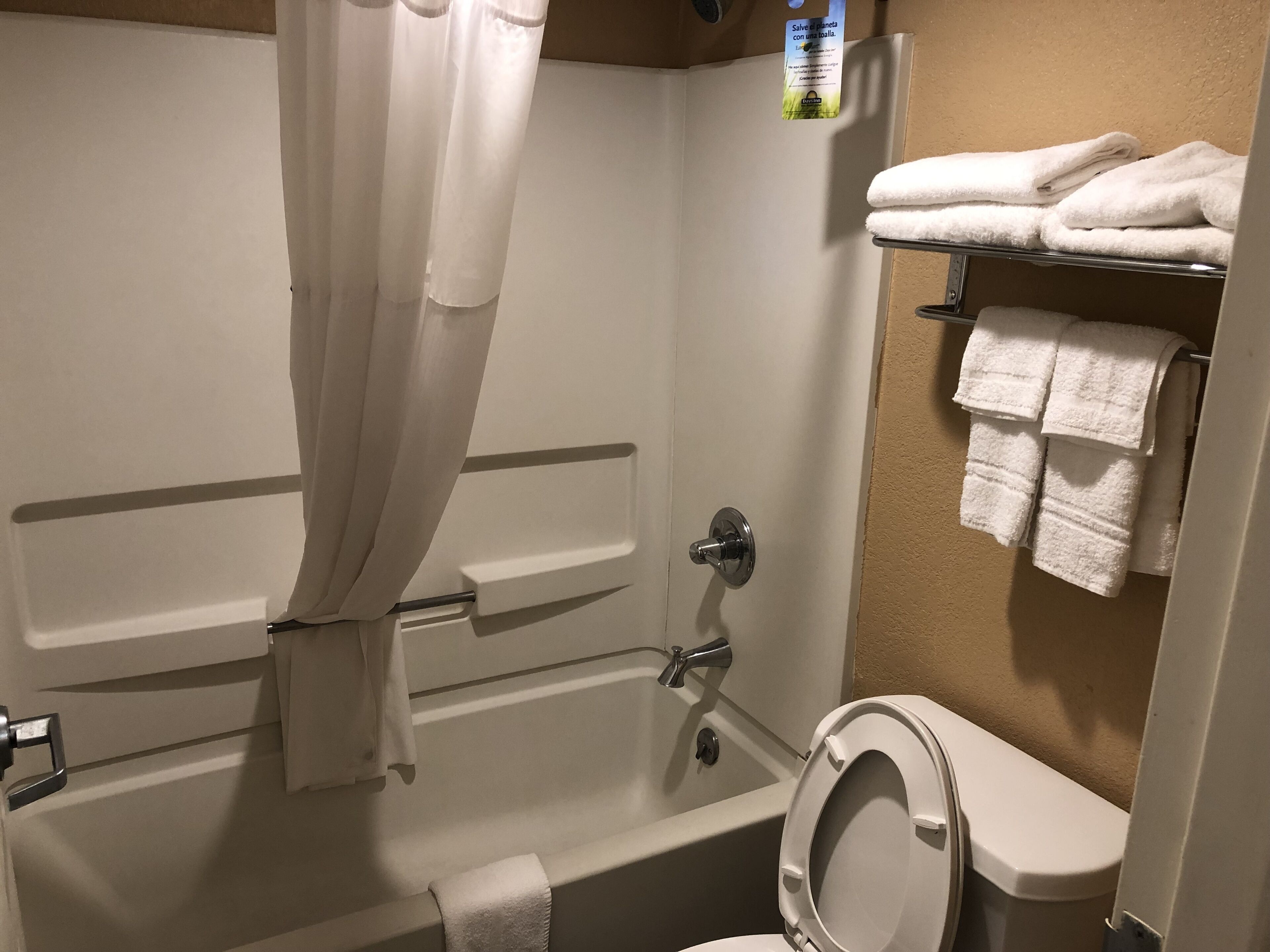 A bathroom with a bathtub, toilet, and a towel rack with folded towels.