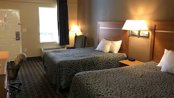 Habitación de hotel con dos camas, una silla, un escritorio y un ventanal con cortinas.
