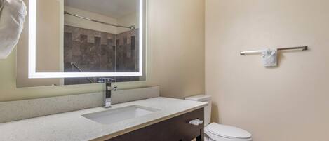 A bathroom with a large mirror, a sink, a toilet, and a towel rack.