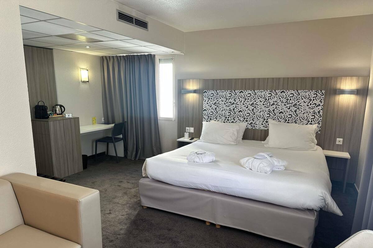 Una habitación de hotel con cama, escritorio, silla y sofá.