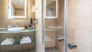 Un baño moderno con cabina de ducha de vidrio, encimera de vidrio y un espejo grande.