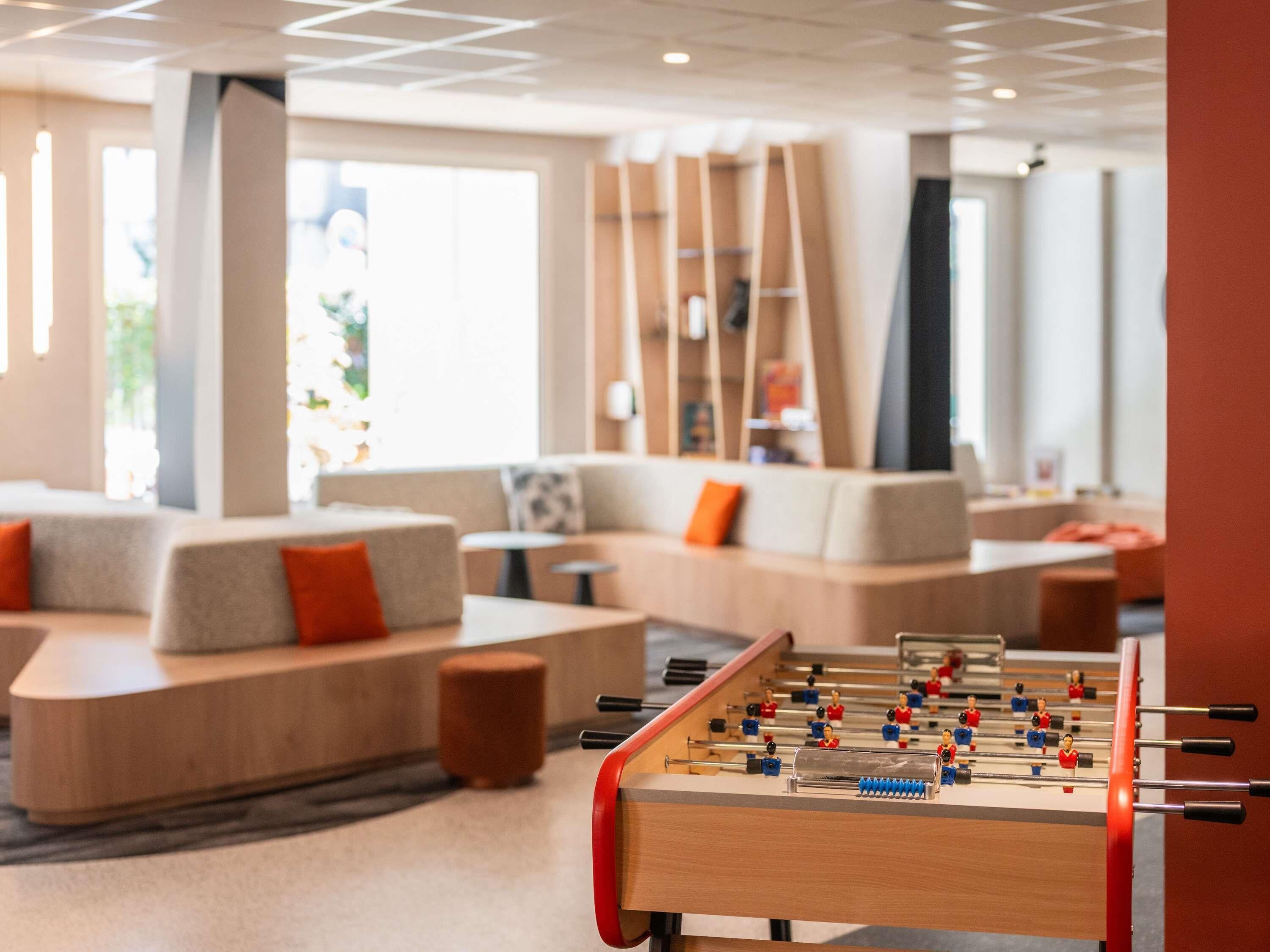 Un espace de détente moderne avec des canapés, une table de baby-foot et une bibliothèque.