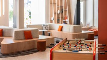 Un espace de détente moderne avec des canapés, une table de baby-foot et une bibliothèque.