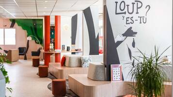 Un intérieur moderne comprenant un comptoir d’accueil, des espaces d’attente et un mur orné d’un motif graphique.
