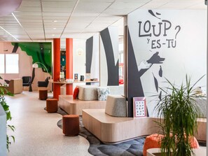 Un intérieur moderne comprenant un comptoir d’accueil, des espaces d’attente et un mur orné d’un motif graphique.