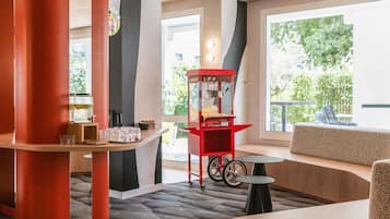 A modern interior with a seating area, a popcorn machine, and a window with a view of greenery.
