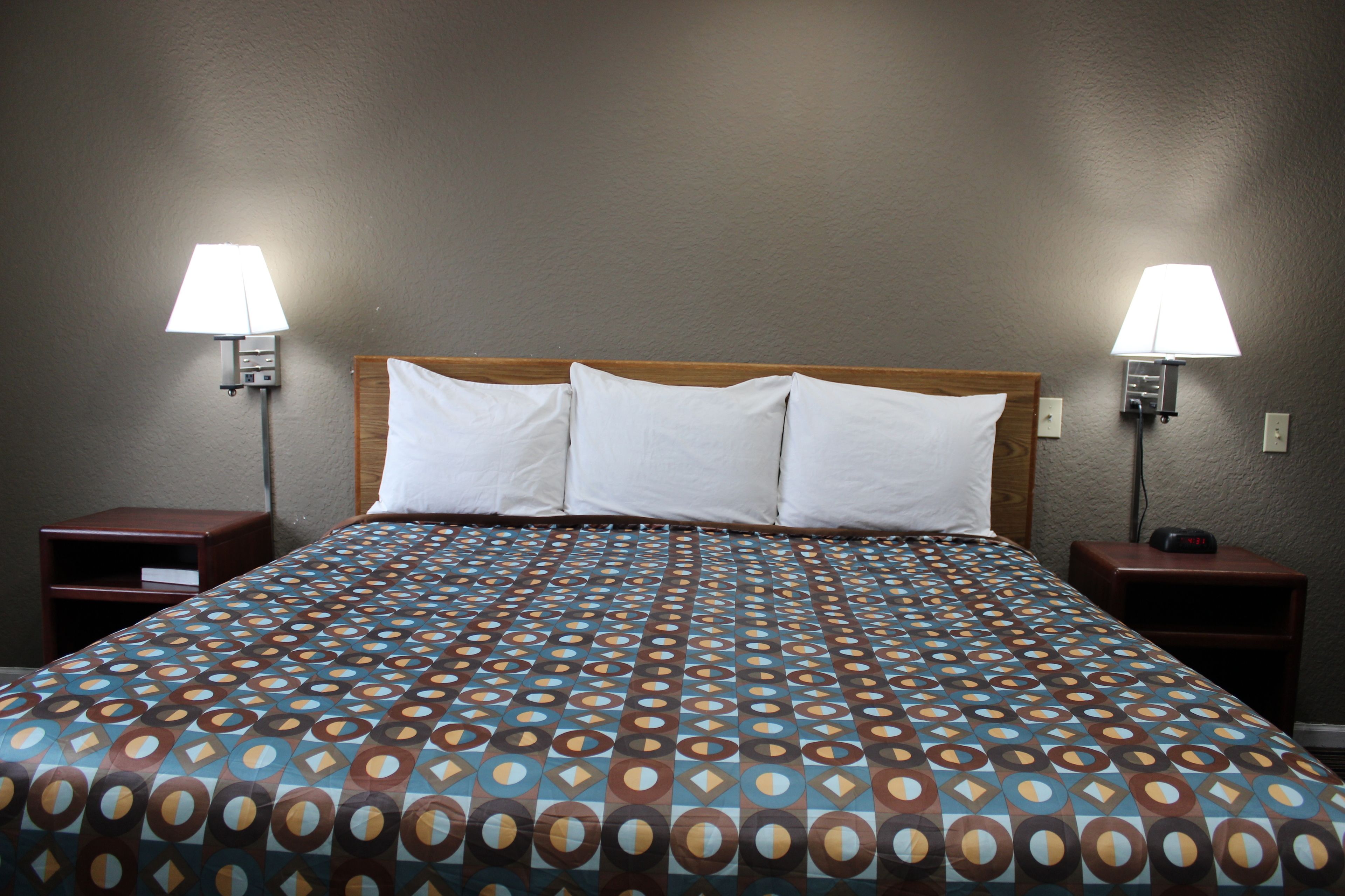 A hotel room with a large bed, two bedside tables, and two wall-mounted lamps.