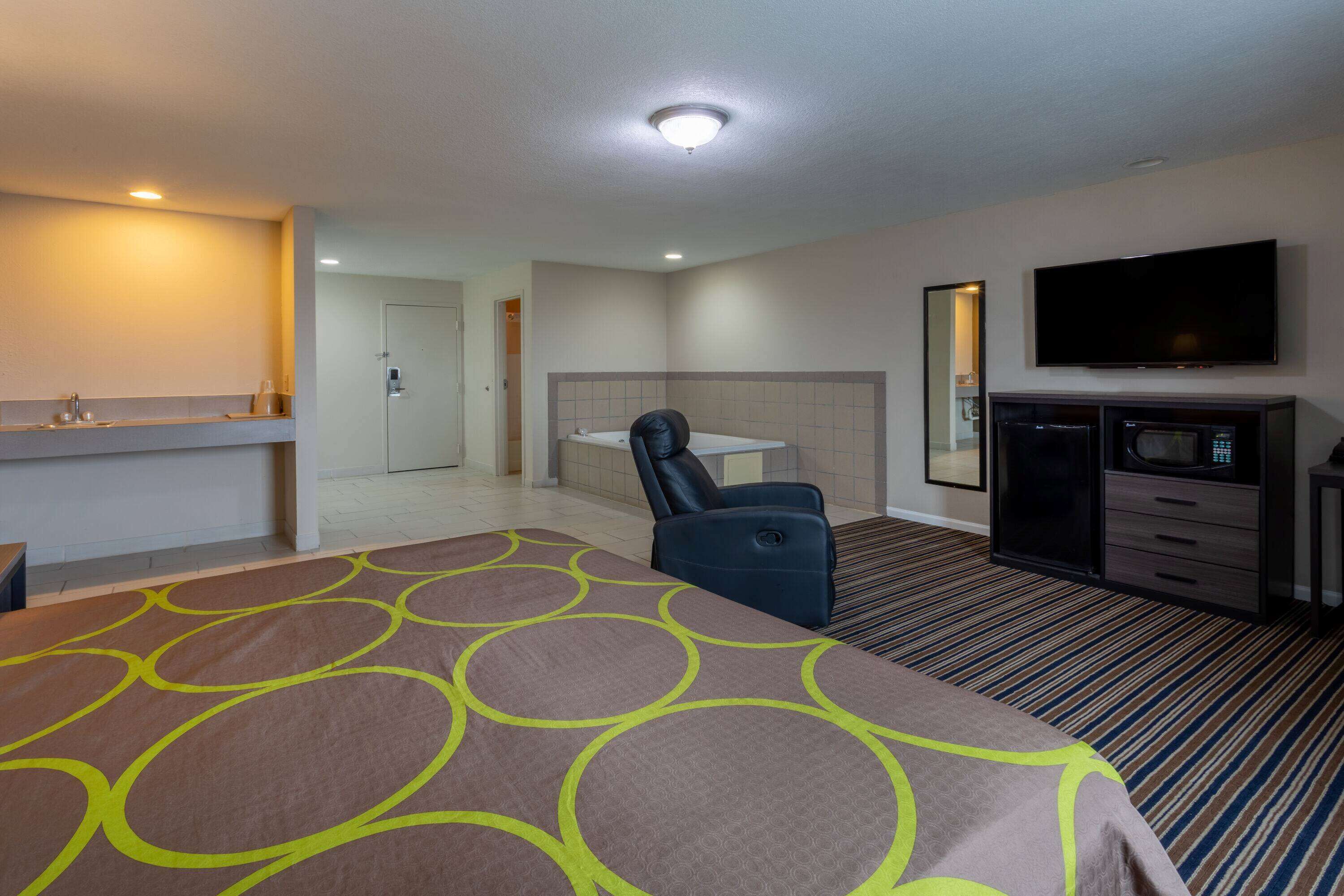 A hotel room with a bed, a TV, a desk, and a chair.