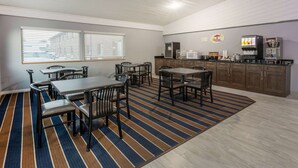 Un espace repas avec un tapis à rayures, des tables et des chaises en bois.