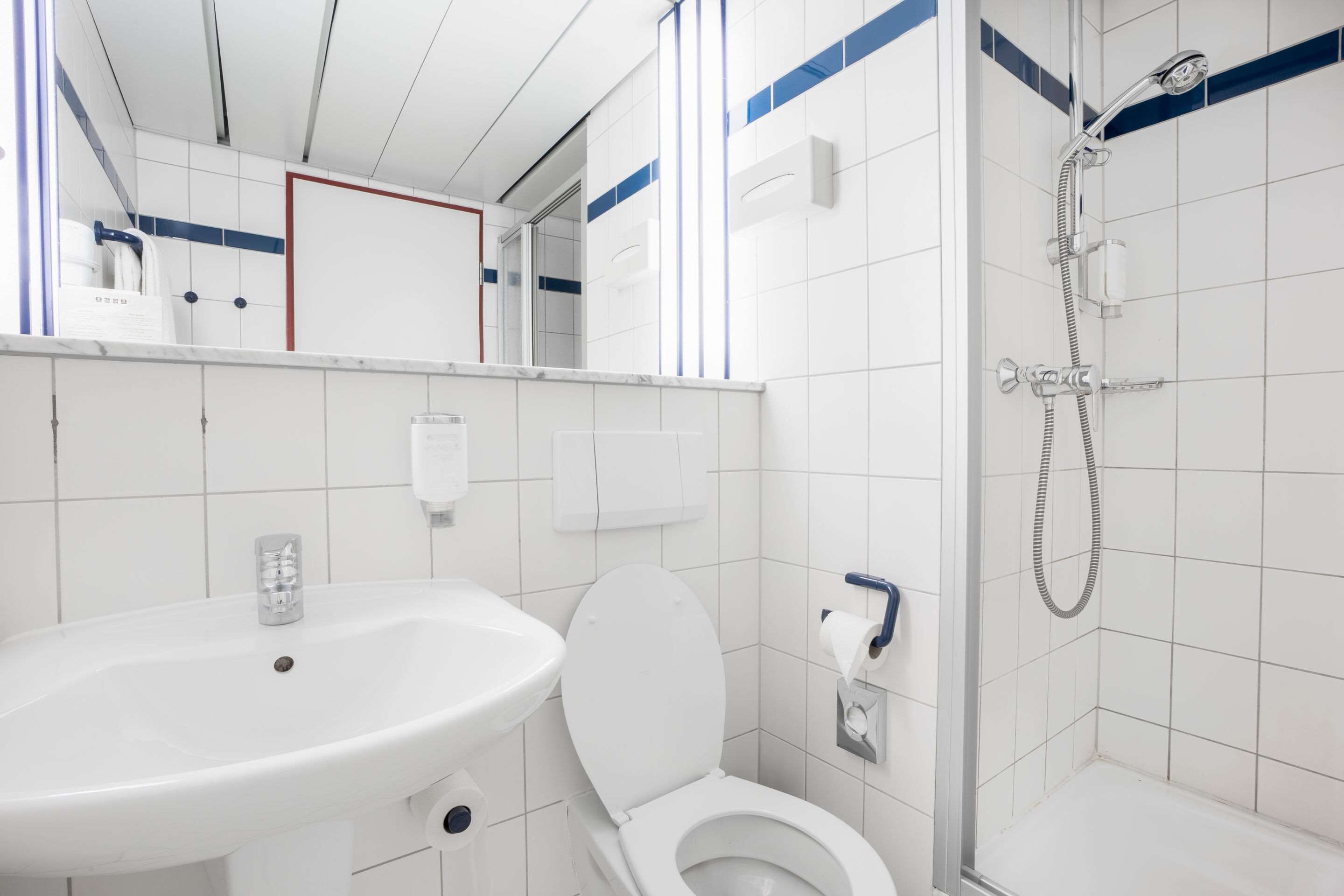 Un baño moderno con lavamanos, inodoro y ducha blancos.