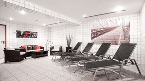 Un área de espera moderna con un sofá, sillones y un gran mural en la pared.