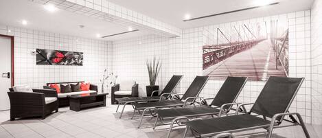 Un área de espera moderna con un sofá, sillones y un gran mural en la pared.