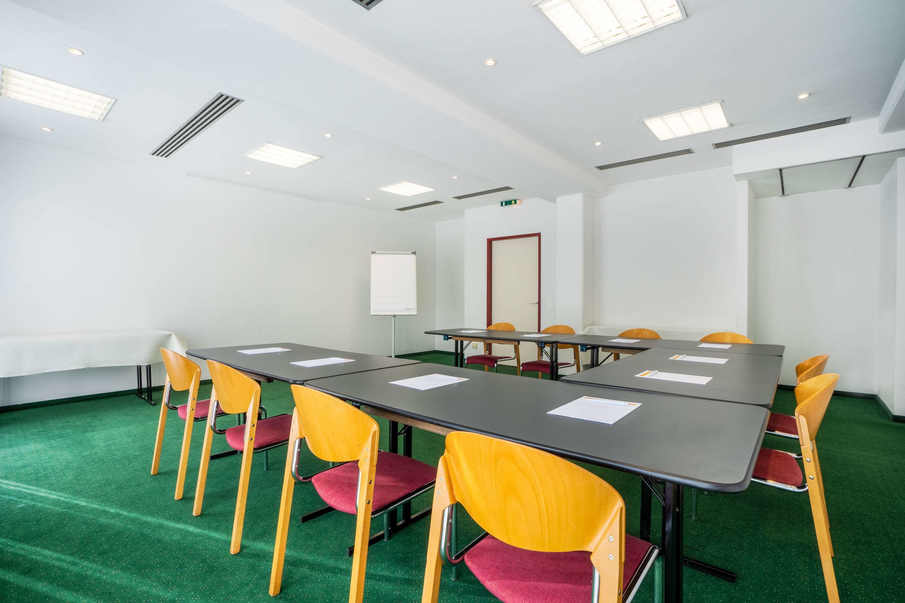 A conference room with a long table, yellow chairs, and a whiteboard.