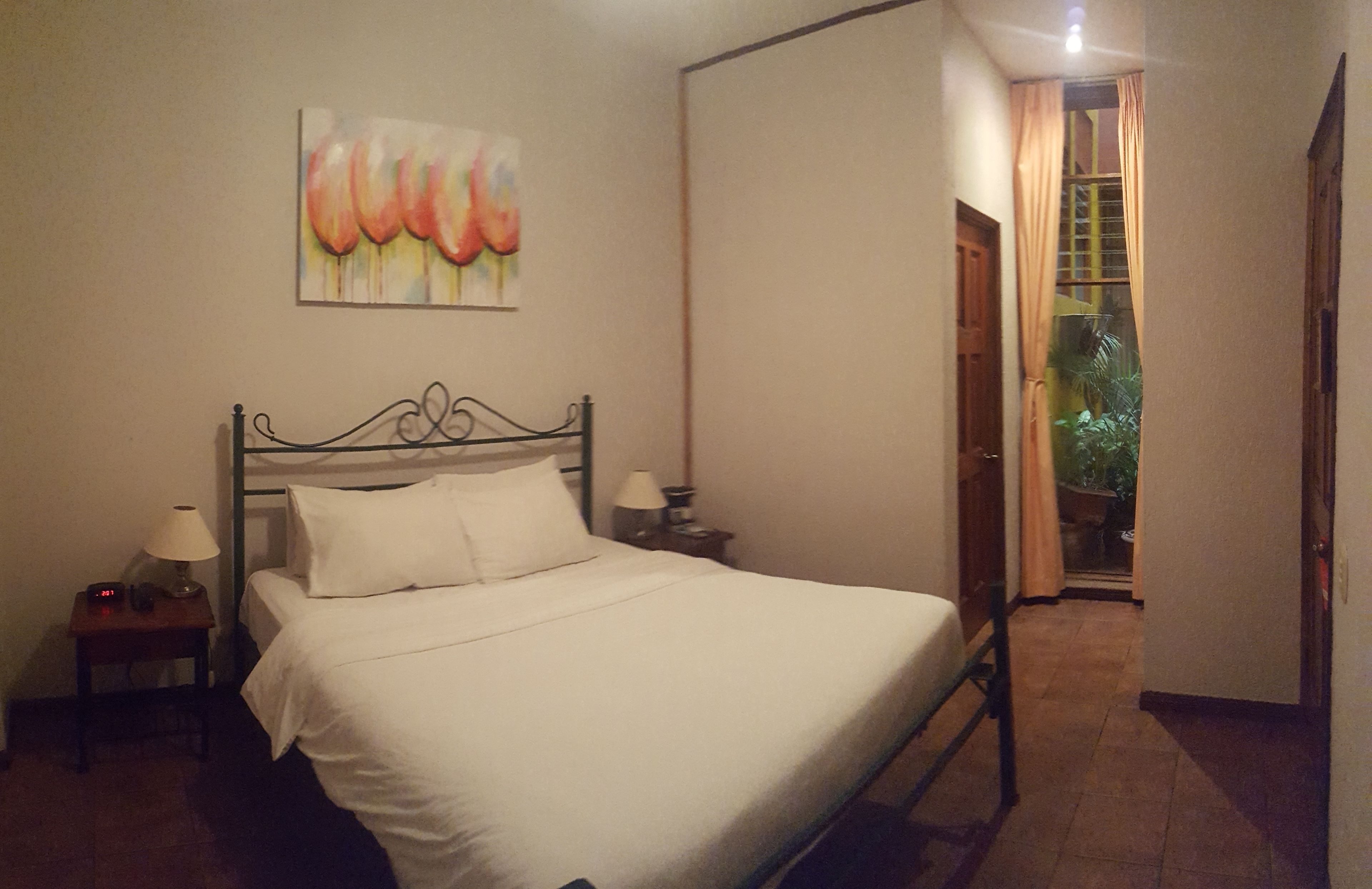 Ein Schlafzimmer mit einem Bett, einem Nachttisch, einer Lampe und einem Bild an der Wand.