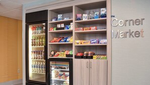 Une petite épicerie de quartier avec des distributeurs de boissons réfrigérées et des étagères remplies de collations et de boissons.
