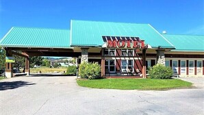A motel with a green roof, a prominent 'MOTEL' sign, and a covered parking area. - Elkhorn Mountain Inn (Clancy)