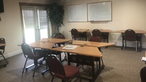 A conference room with a large table, chairs, a plant, and a whiteboard. - Elkhorn Mountain Inn (Clancy)