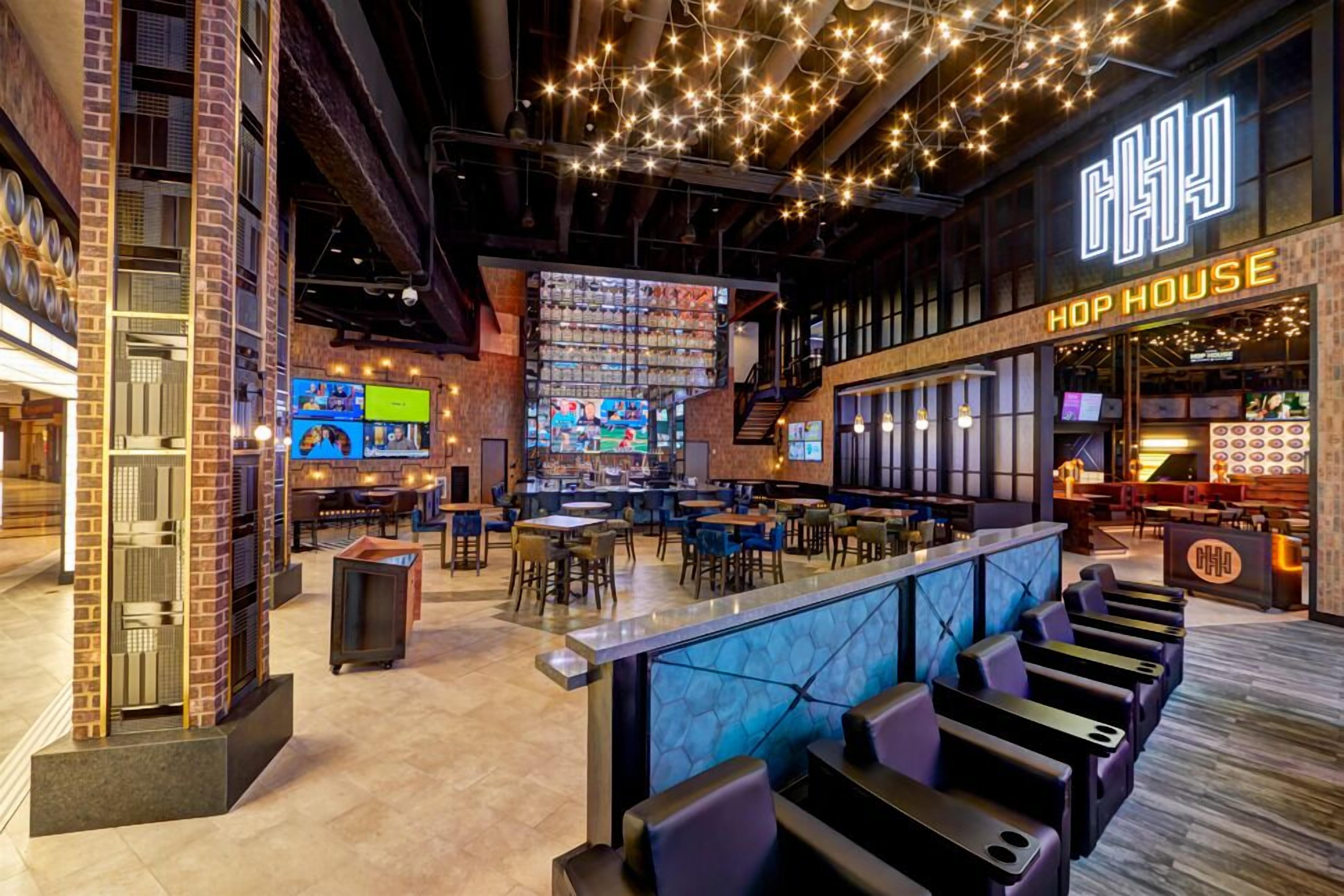 A bar area with multiple seating options, a counter, and a neon sign reading 'HOP HOUSE'.