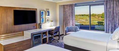 A hotel room with a large bed, a desk with a chair, a flat-screen TV, and a large window with a view of a golf course.
