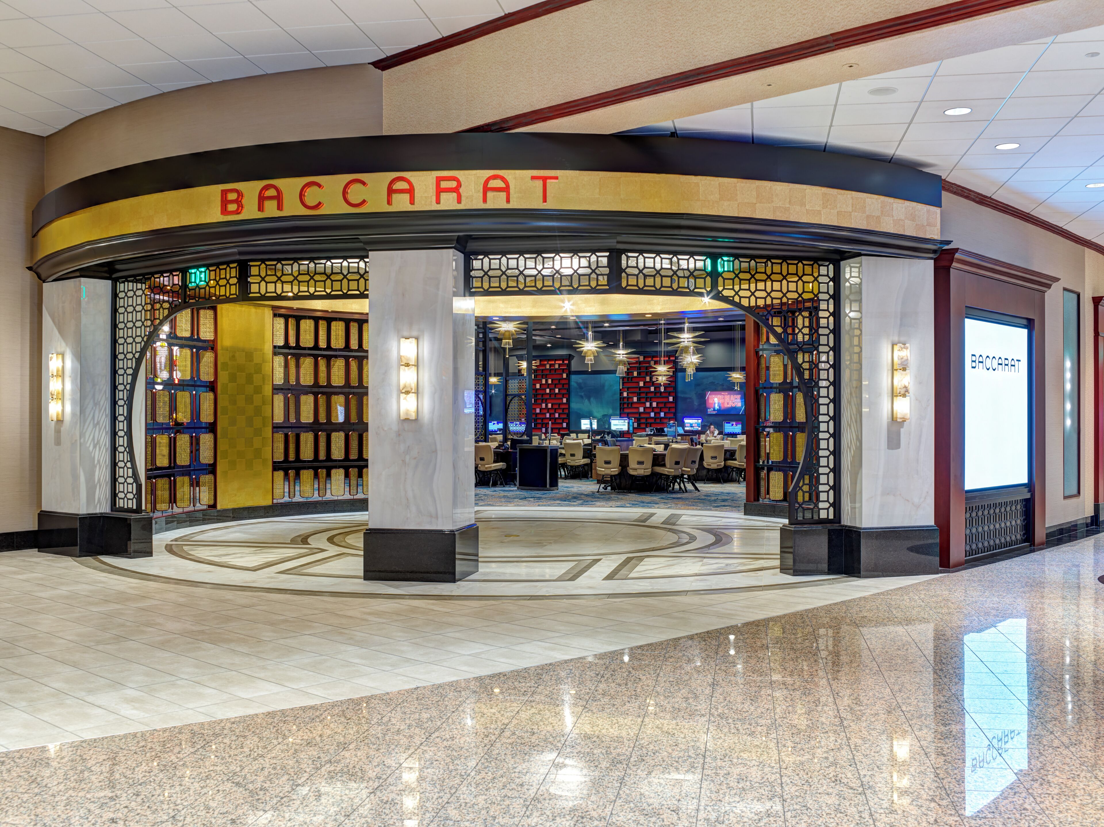 Lobby di un hotel Baccarat con pavimento a scacchi, una reception e un'area salotto.