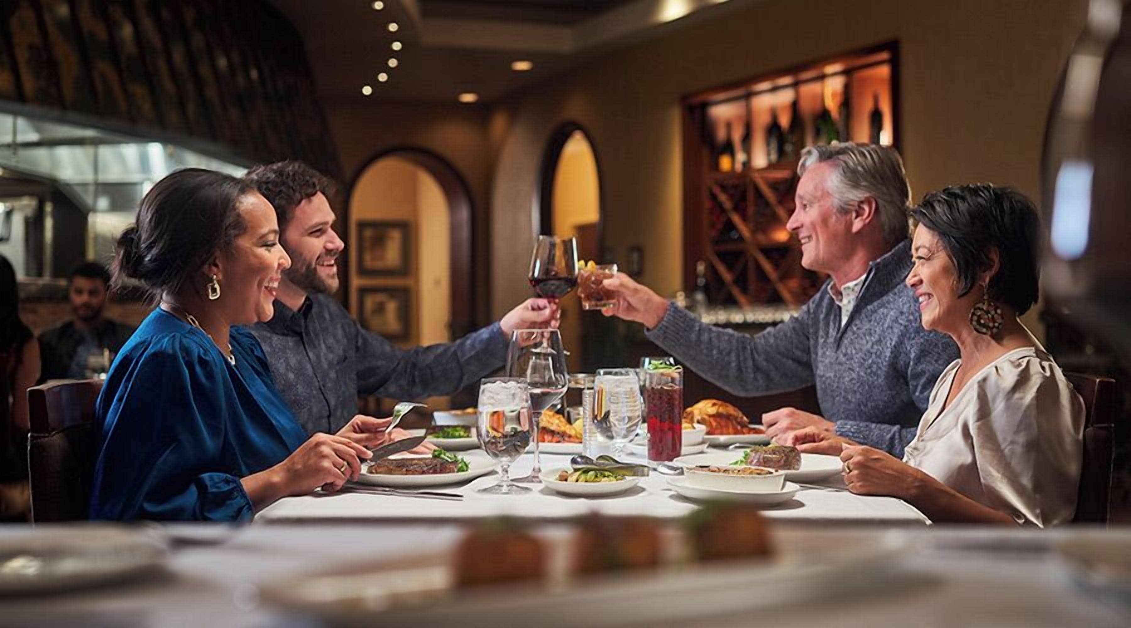 Un gruppo di persone cena in un ristorante, con una varietà di piatti e bevande sul tavolo.