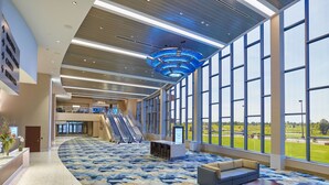 A spacious lobby with a curved carpet, seating area, and large windows offering a view of the outdoors.