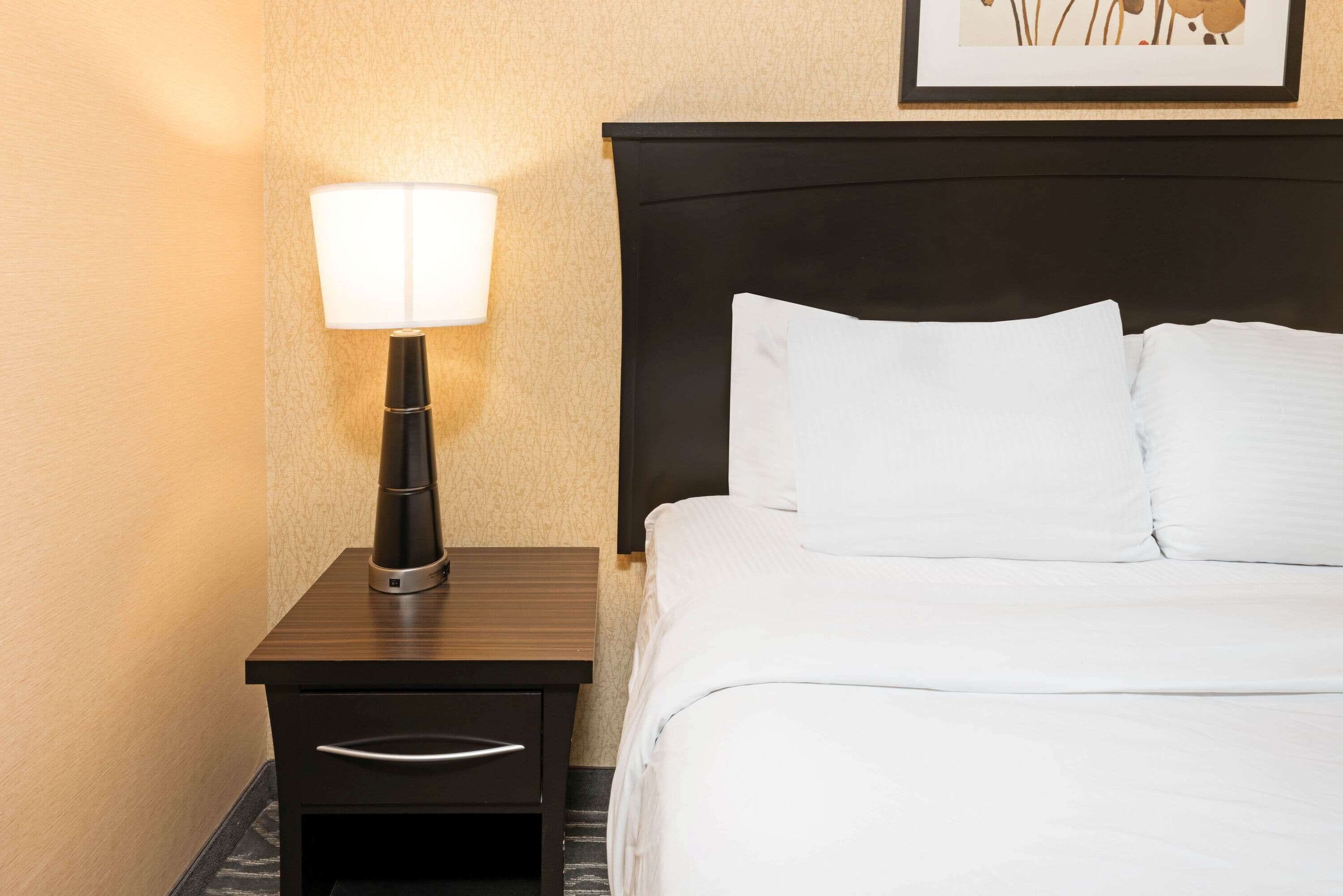 A neatly made bed with white linens and a dark headboard.