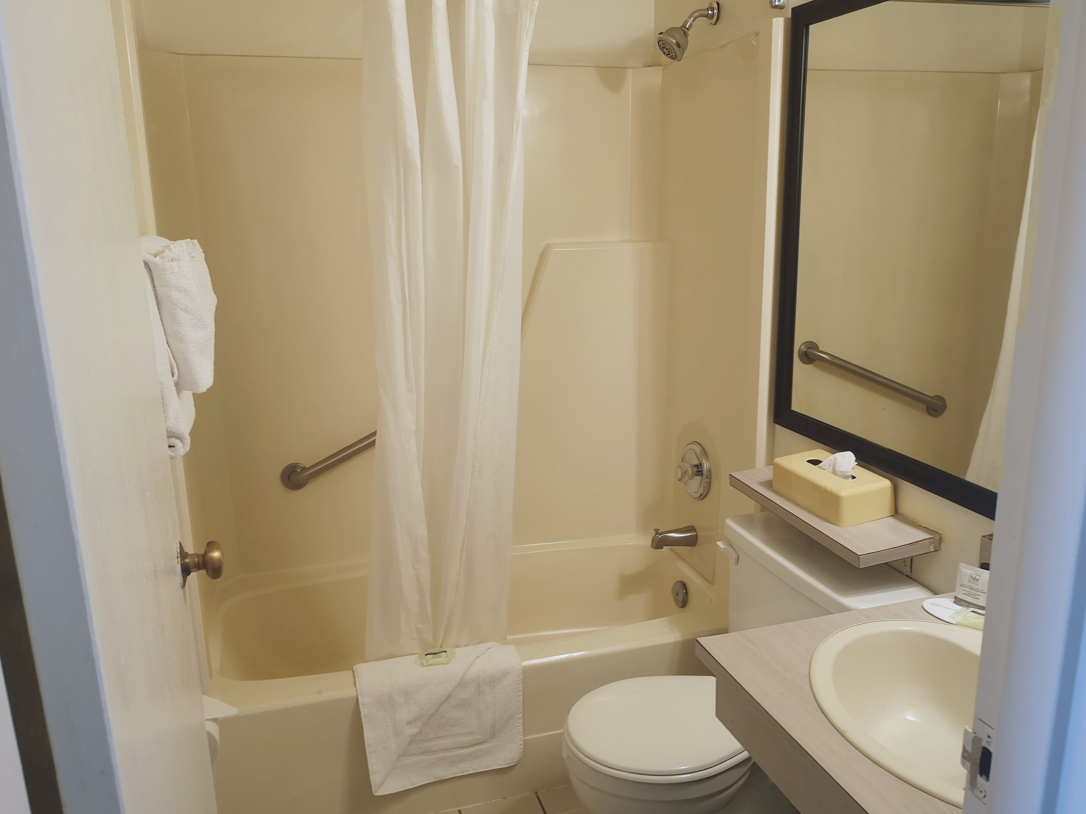 A bathroom with a bathtub, toilet, sink, and a mirror.