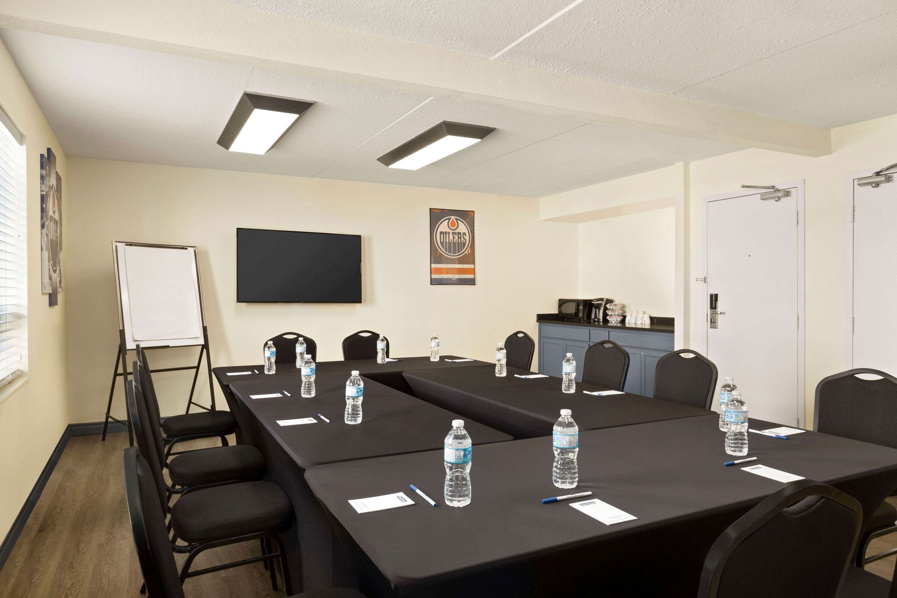 Un salón de conferencias con una larga mesa, sillas, botellas de agua y una pizarra.