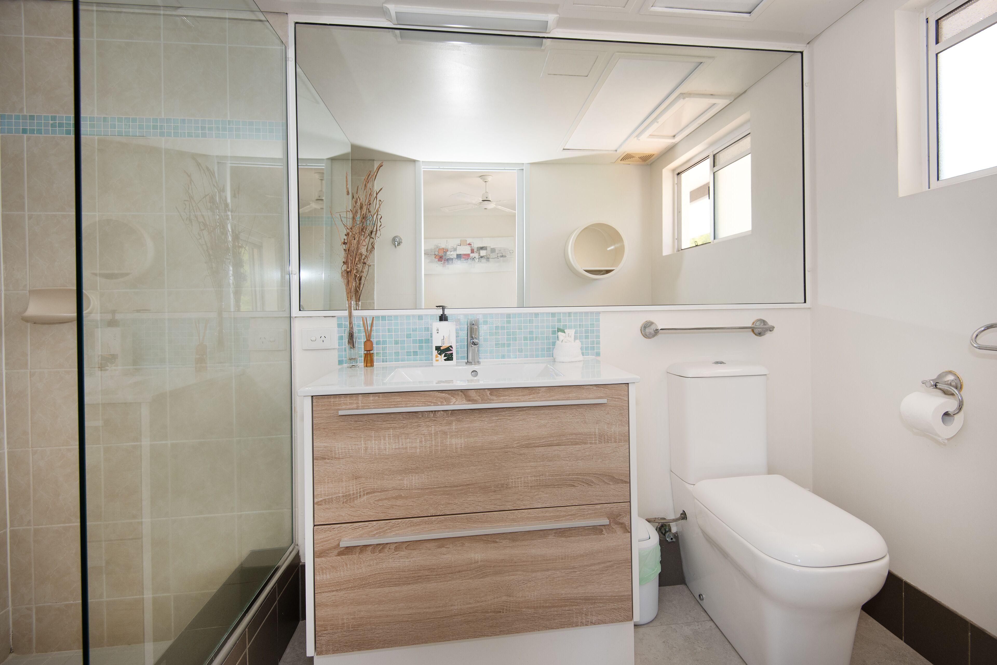 Un bagno moderno con cabina doccia in vetro, un water bianco e un mobile lavabo con specchio.