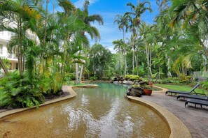 Een tropisch resort met een fontein, palmbomen en comfortabele zitgedeeltes.